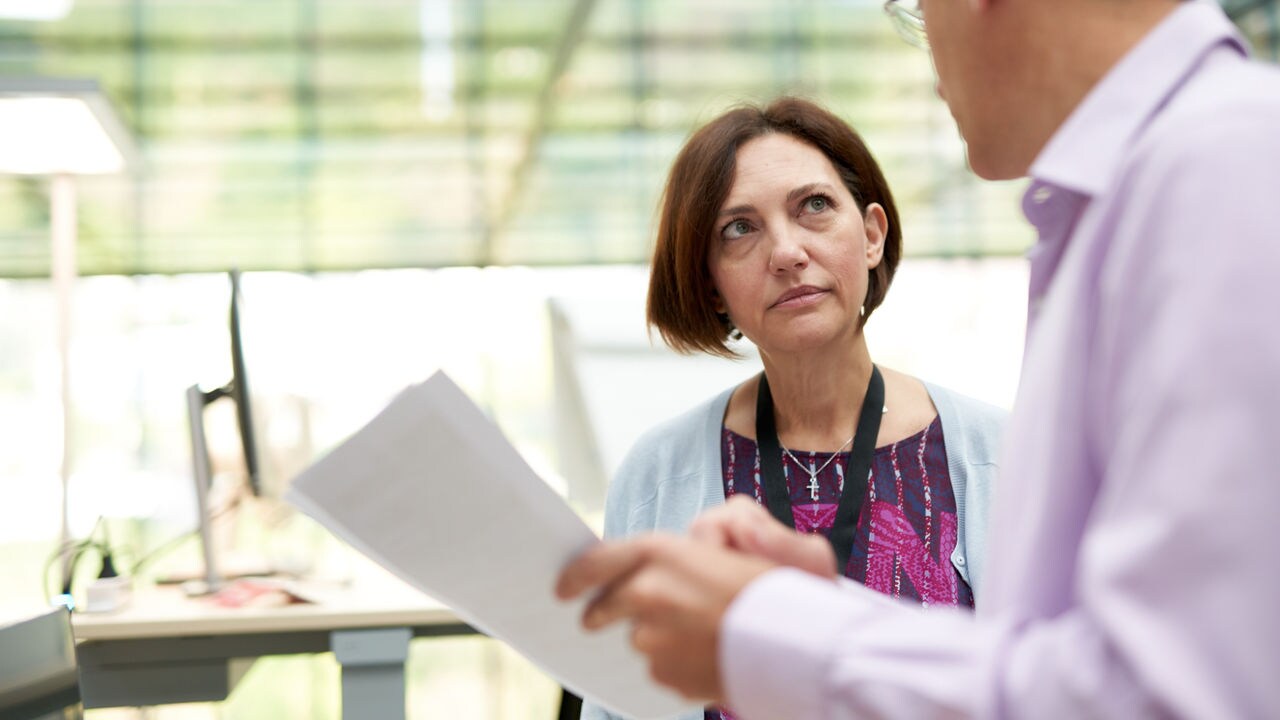 Two coworkers having a conversation in an office