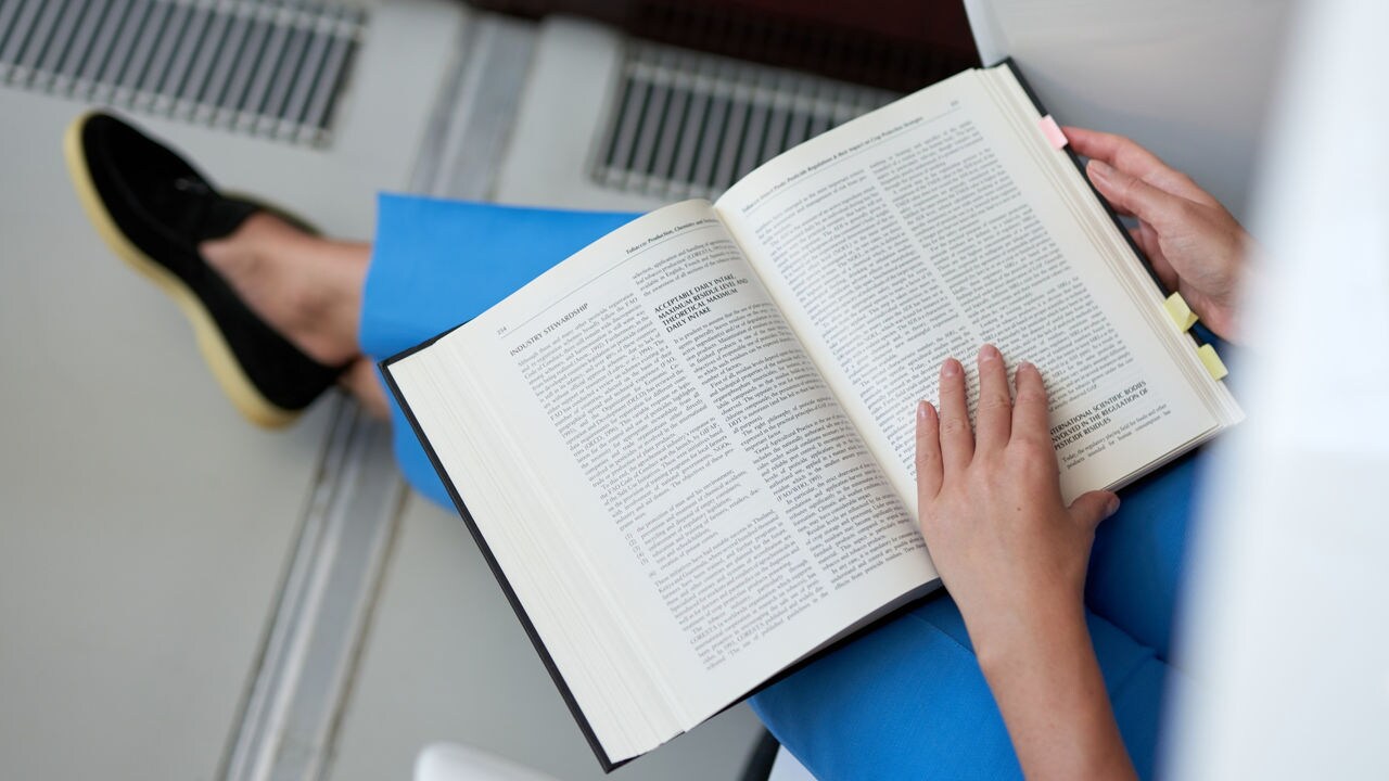 Person sitting on a chair and reading scientific book.